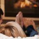 Couple sitting on sofa at home in front of fireplace, rear view.